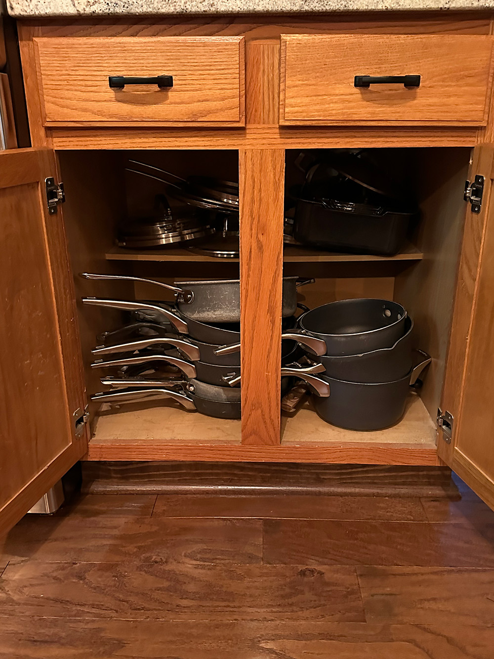 Before- Kitchen cabinets jammed with towering pots and pans and doors open